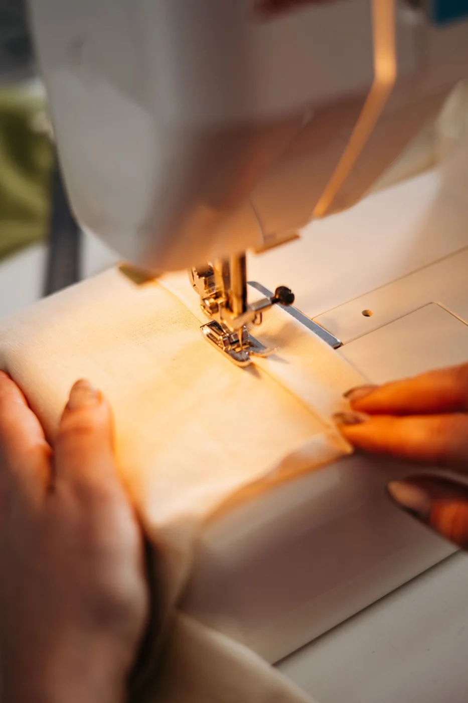 Hands guiding cloth through a sewing machine